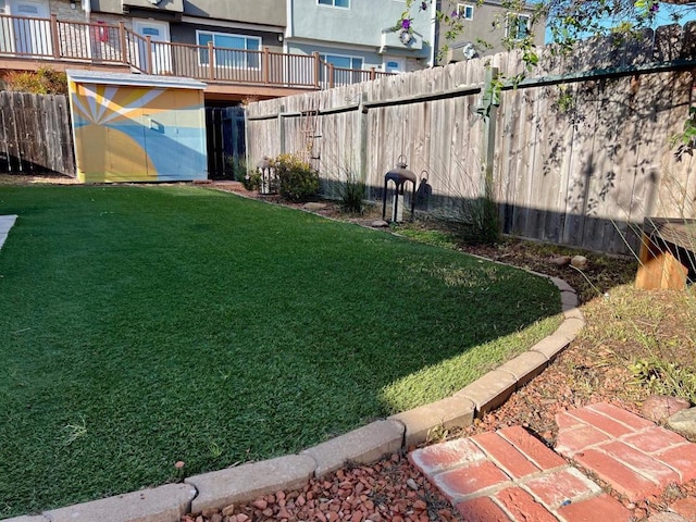 view of yard with an outdoor structure, a fenced backyard, and a shed