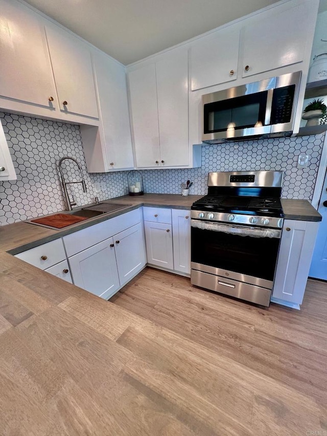 kitchen with dark countertops, light wood-style flooring, appliances with stainless steel finishes, and a sink