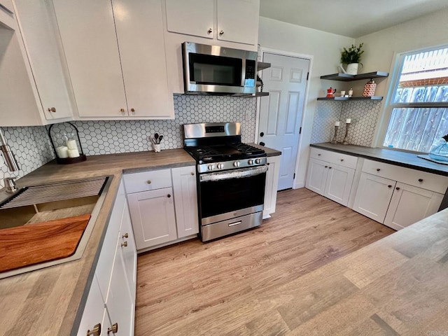 kitchen featuring light wood finished floors, stainless steel appliances, and white cabinets