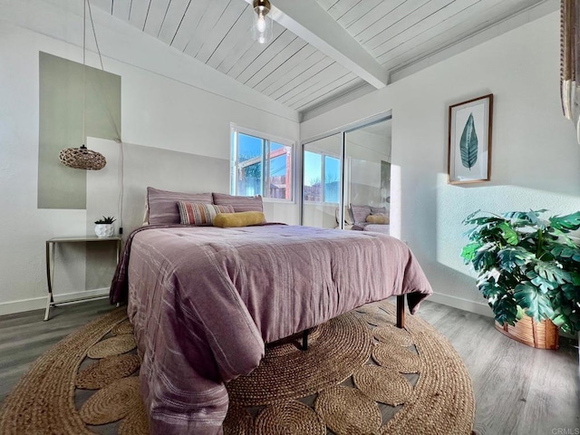 bedroom with wooden ceiling, wood finished floors, baseboards, and vaulted ceiling with beams