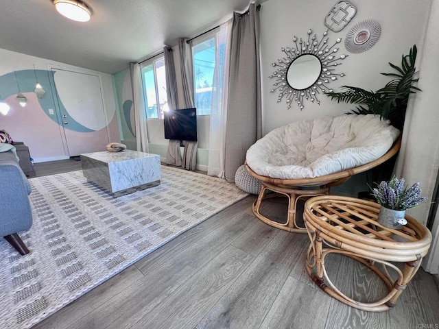 living area with lofted ceiling, baseboards, and wood finished floors