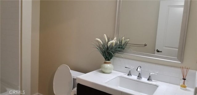 bathroom with vanity, toilet, and tasteful backsplash