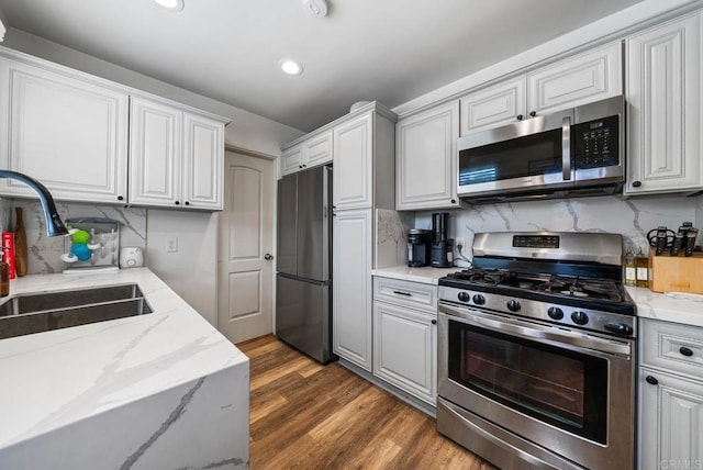 kitchen featuring backsplash, light wood-style floors, stainless steel appliances, and a sink