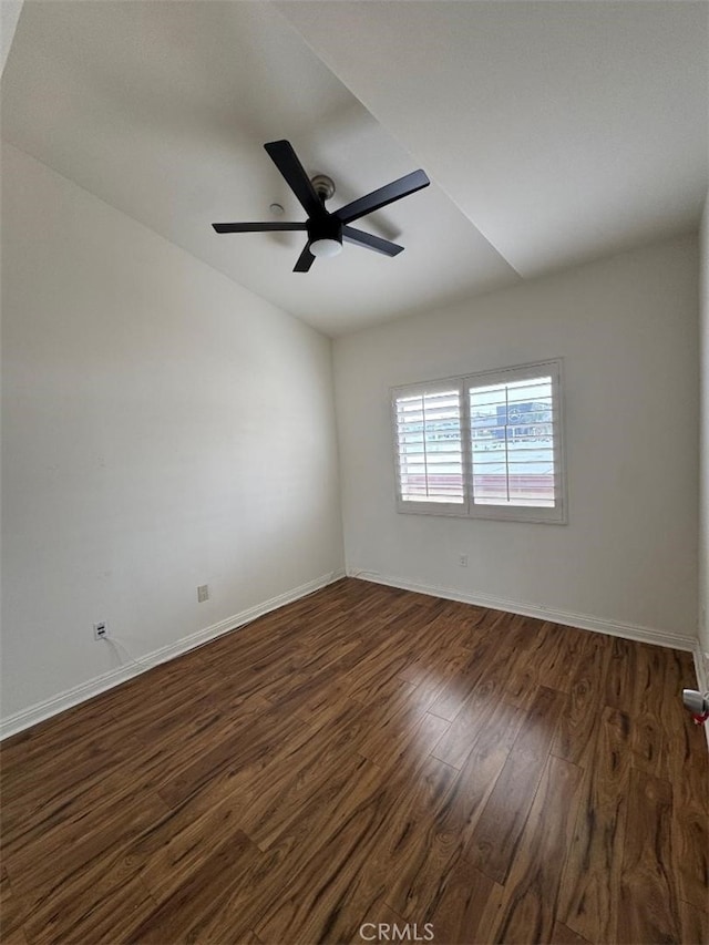 empty room featuring vaulted ceiling, baseboards, ceiling fan, and dark wood-style floors