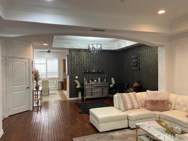 living room with a tray ceiling, ornamental molding, ceiling fan with notable chandelier, and hardwood / wood-style flooring