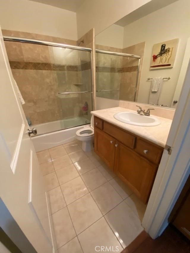 bathroom featuring tile patterned floors, toilet, enclosed tub / shower combo, and vanity