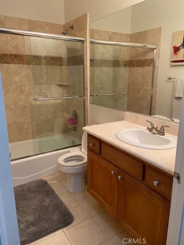 bathroom with bath / shower combo with glass door, tile patterned flooring, vanity, and toilet