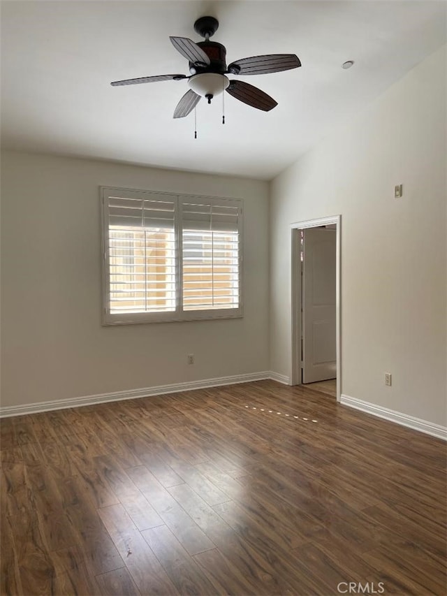 empty room featuring baseboards, dark wood finished floors, ceiling fan, and vaulted ceiling