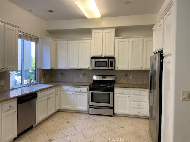 kitchen with light tile patterned floors, a sink, white cabinets, backsplash, and appliances with stainless steel finishes