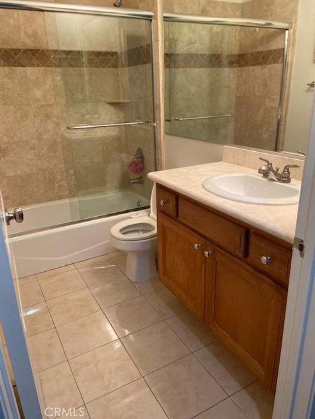 full bathroom featuring toilet, tile patterned flooring, vanity, and combined bath / shower with glass door