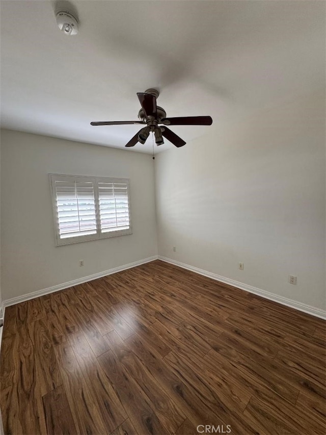 spare room featuring baseboards, dark wood-style flooring, and a ceiling fan