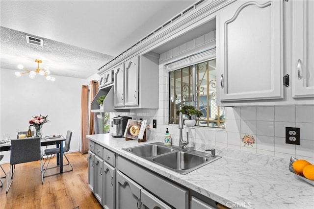 11348 Ramona Ave, Pomona, CA 91766 - kitchen featuring a sink, gray cabinets, visible vents, light wood finished floors, and a notable chandelier