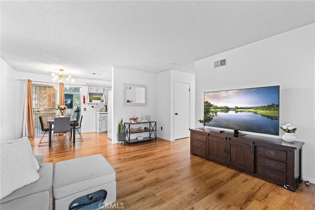 11348 Ramona Ave, Pomona, CA 91766 - living area with light wood finished floors, a textured ceiling, a notable chandelier, and visible vents
