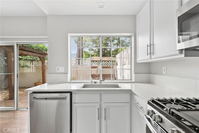1092 Amberton Ln, Newbury Park, CA 91320 - kitchen featuring appliances with stainless steel finishes, a sink, white cabinetry, light countertops, and wood finished floors