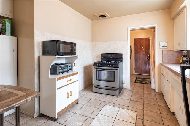1257 E 76th Pl, Los Angeles, CA 90001 - kitchen featuring gas stove, black microwave, light countertops, backsplash, and light tile patterned floors
