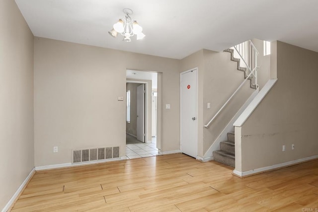 spare room featuring visible vents, wood finished floors, baseboards, and stairs
