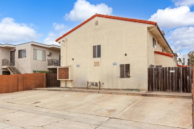 exterior space with stucco siding, fence, and uncovered parking
