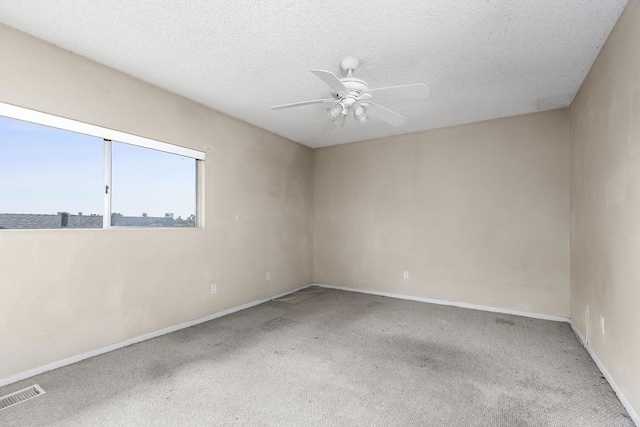 carpeted spare room featuring ceiling fan, a textured ceiling, baseboards, and visible vents