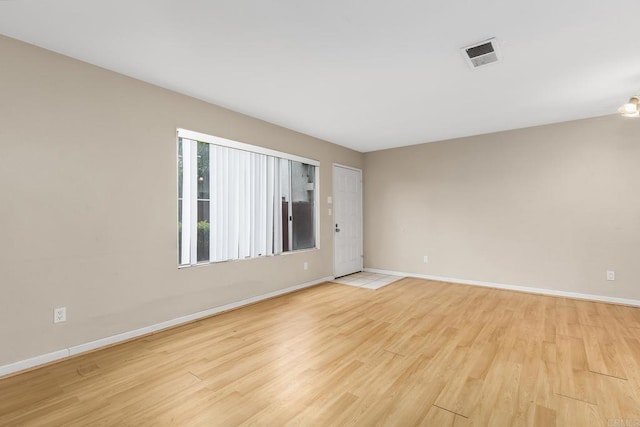 empty room featuring baseboards, light wood-style floors, and visible vents