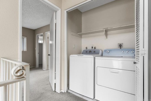 laundry room featuring washer and dryer, laundry area, a textured ceiling, and light carpet