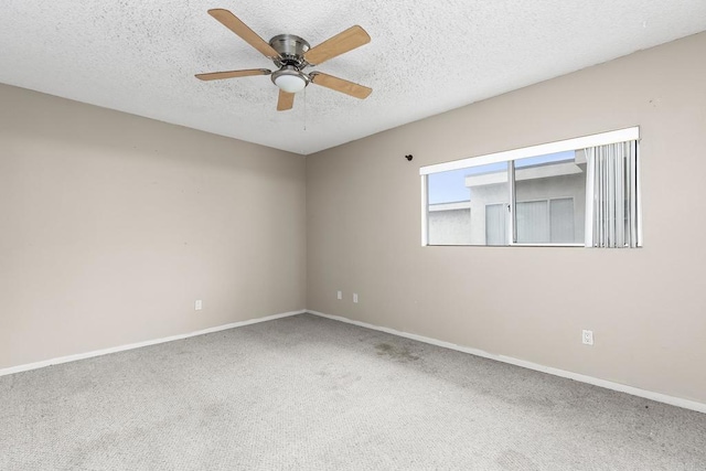 carpeted empty room with a textured ceiling, baseboards, and a ceiling fan