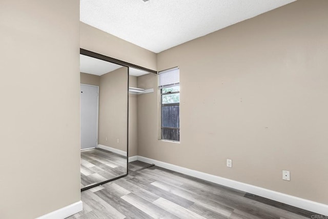 unfurnished bedroom with baseboards, a closet, and wood finished floors