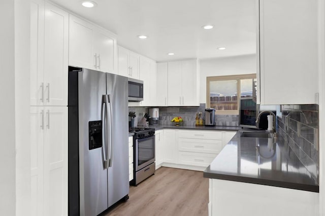 kitchen featuring a sink, white cabinetry, decorative backsplash, dark countertops, and appliances with stainless steel finishes
