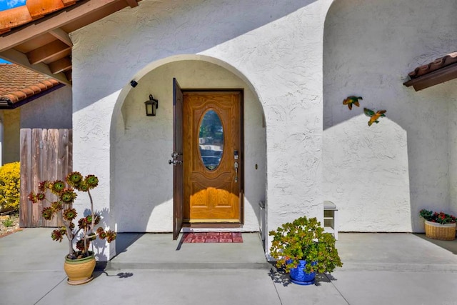 entrance to property with a tiled roof and stucco siding