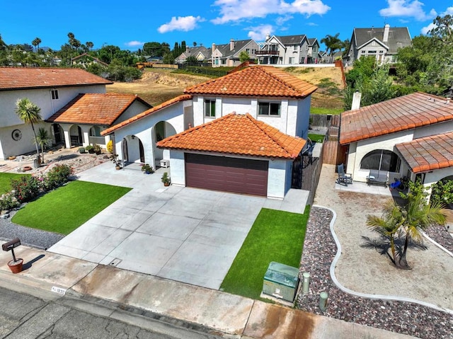mediterranean / spanish-style house featuring driveway, stucco siding, a residential view, and a tile roof