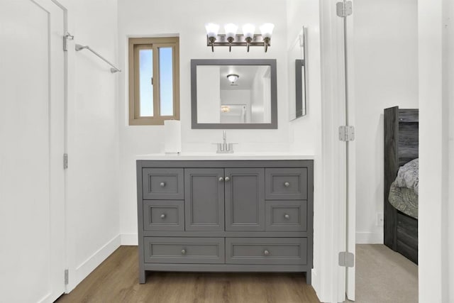 bathroom with wood finished floors, baseboards, and vanity