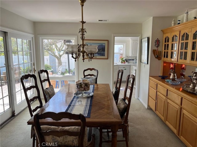 dining room with an inviting chandelier, light carpet, and visible vents