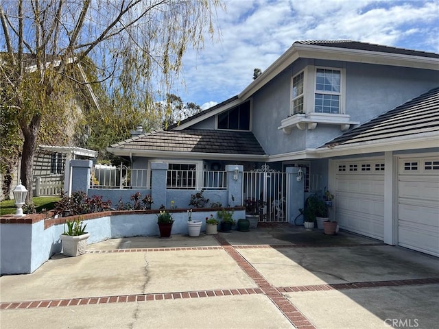 traditional-style house featuring concrete driveway, stucco siding, a tile roof, and fence