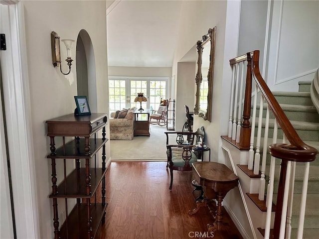 hallway featuring arched walkways, stairs, and wood finished floors