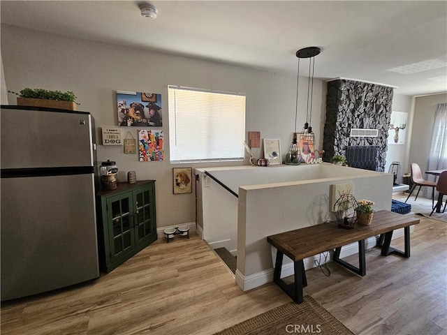 kitchen featuring freestanding refrigerator, light wood-type flooring, and baseboards