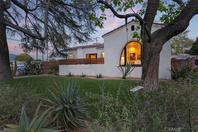 312 W Lutge Ave, Burbank, CA 91506 - view of front of house featuring stucco siding, a tile roof, fence, and a lawn