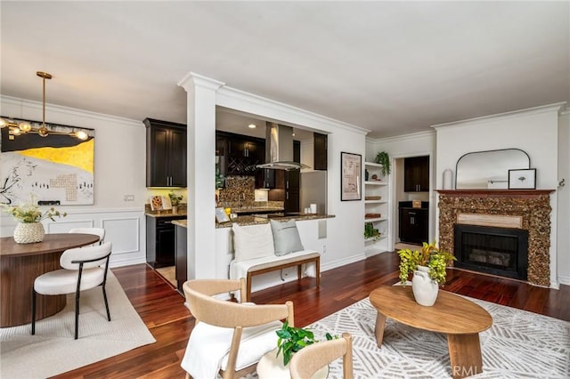 living area with dark wood finished floors, ornamental molding, and a high end fireplace