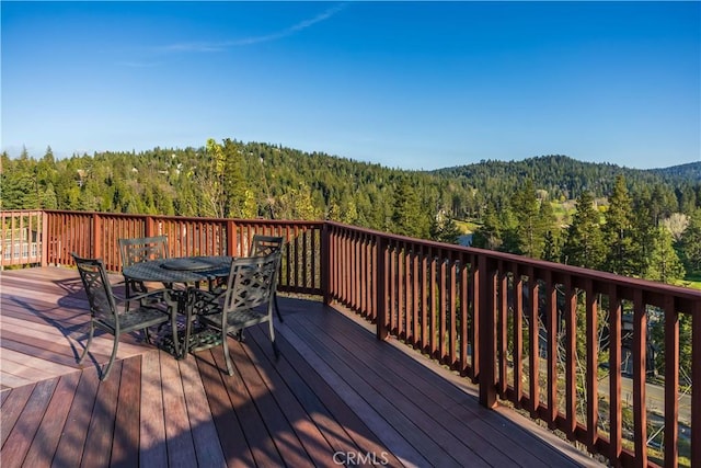wooden deck featuring outdoor dining area and a wooded view