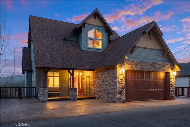 view of front of home featuring stone siding, roof with shingles, aphalt driveway, and covered porch