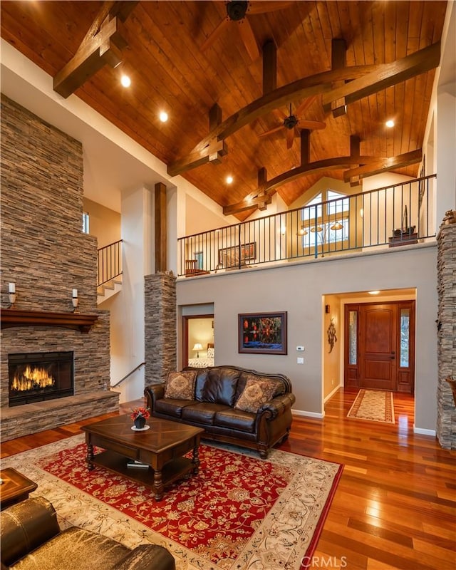 living area with hardwood / wood-style flooring, beam ceiling, high vaulted ceiling, wooden ceiling, and a fireplace