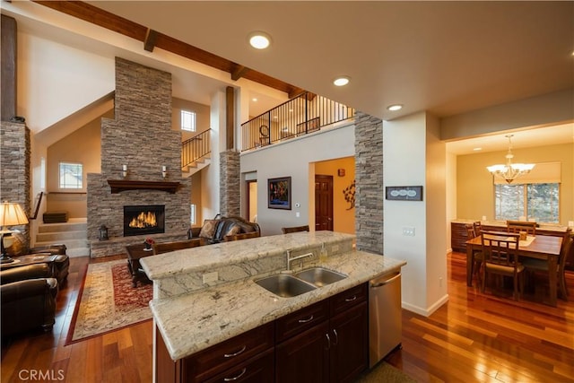 kitchen featuring a sink, dark wood-type flooring, a fireplace, open floor plan, and stainless steel dishwasher