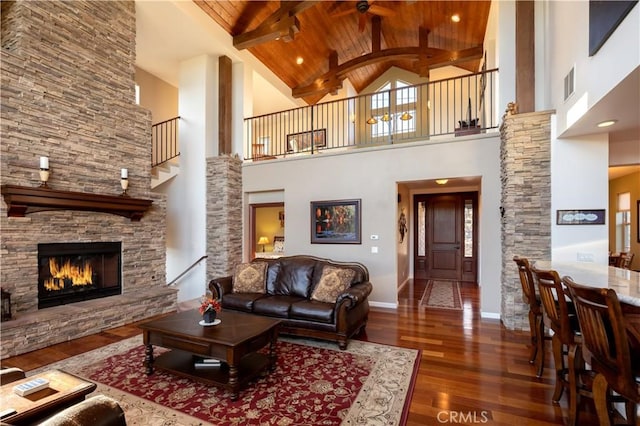 living area with wooden ceiling, visible vents, high vaulted ceiling, hardwood / wood-style floors, and a fireplace