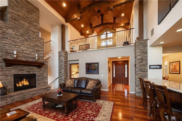 living area with wood ceiling, wood finished floors, high vaulted ceiling, a fireplace, and beamed ceiling