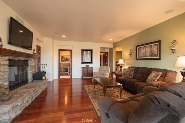 living room featuring recessed lighting, a stone fireplace, and wood finished floors