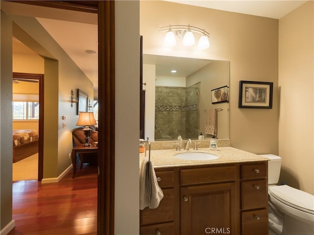 full bath with toilet, wood finished floors, tiled shower, ensuite bath, and vanity
