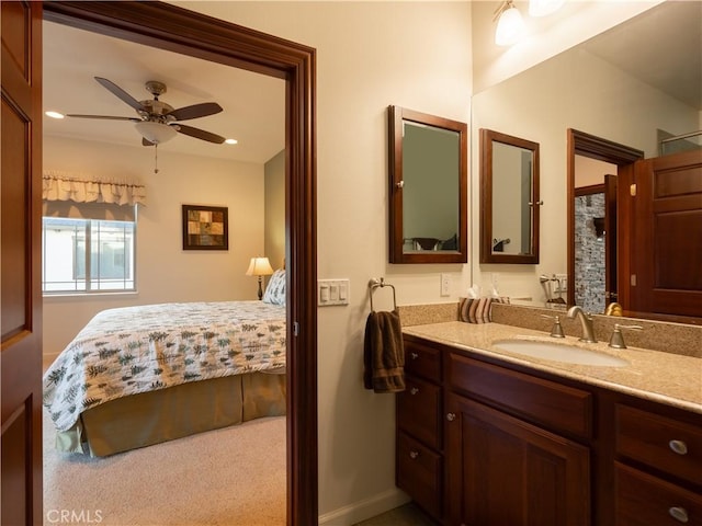 ensuite bathroom featuring vanity, ensuite bath, a ceiling fan, and baseboards