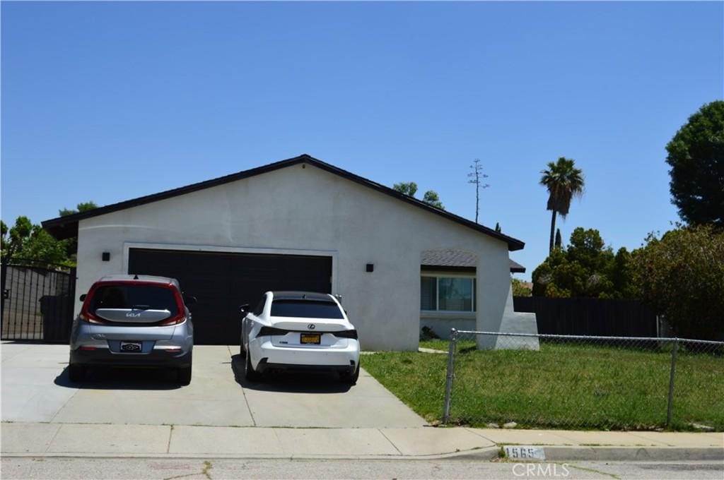 1565 Villa Ct, Highland, CA 92346 - view of side of home featuring stucco siding, concrete driveway, an attached garage, and a gate