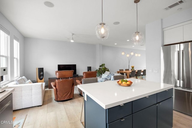 1323 Bayside Cir, Oxnard, CA 93035 - kitchen with freestanding refrigerator, light wood-type flooring, light countertops, decorative light fixtures, and a center island