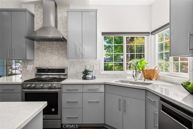 kitchen featuring wall chimney range hood, appliances with stainless steel finishes, and gray cabinets