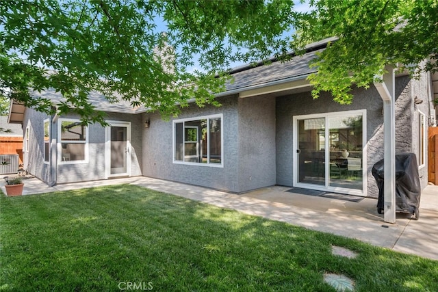 back of house with stucco siding, fence, and a lawn