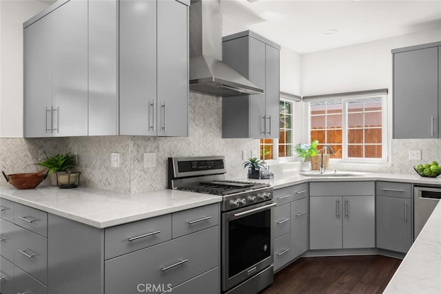 kitchen featuring wall chimney range hood, stainless steel appliances, and gray cabinets